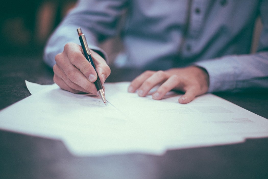 man's hands writing on a paper