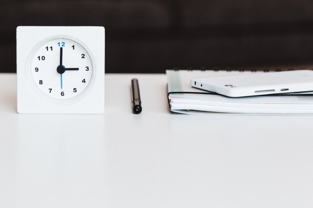 clock and notebook on table