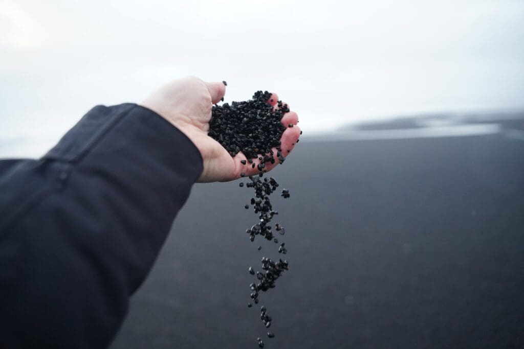 Someone holding black sand from Reynisfjara Beach