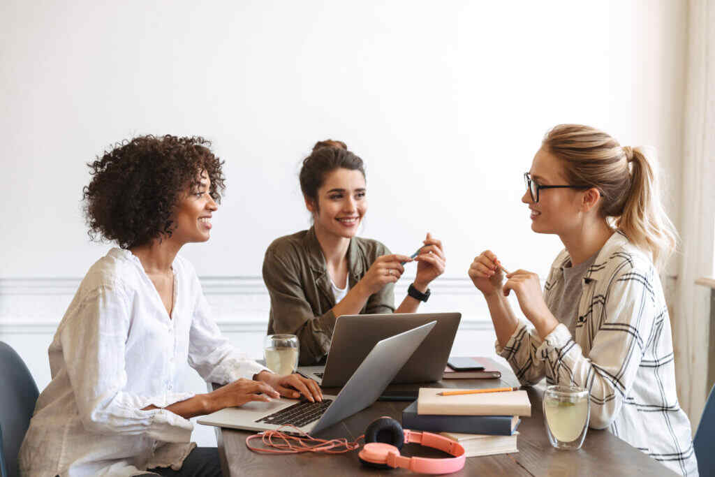 Group of multiethnic cheerful young women studying together at the coffee shop. 