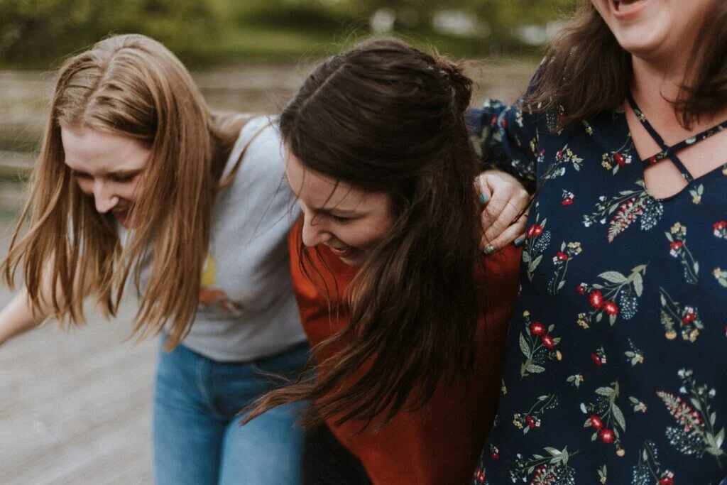 Women holding shoulders and laughing