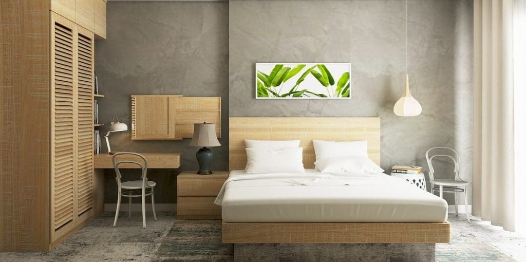 serviced apartment in daytime with wooden bed, slatted wardrobe, desk, white bedlinen, and picture of leaves in daytime