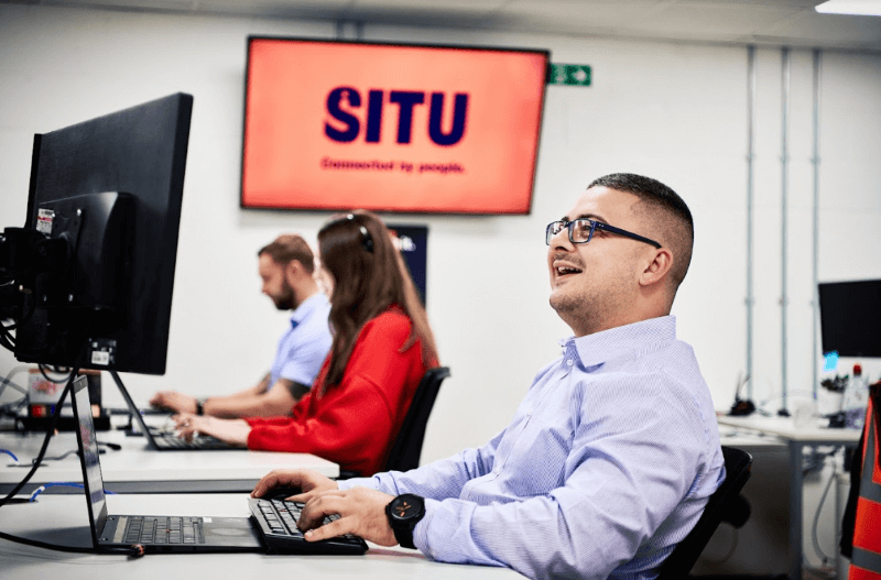 A Situ team member at their desk with the Situ logo on a screen behind them